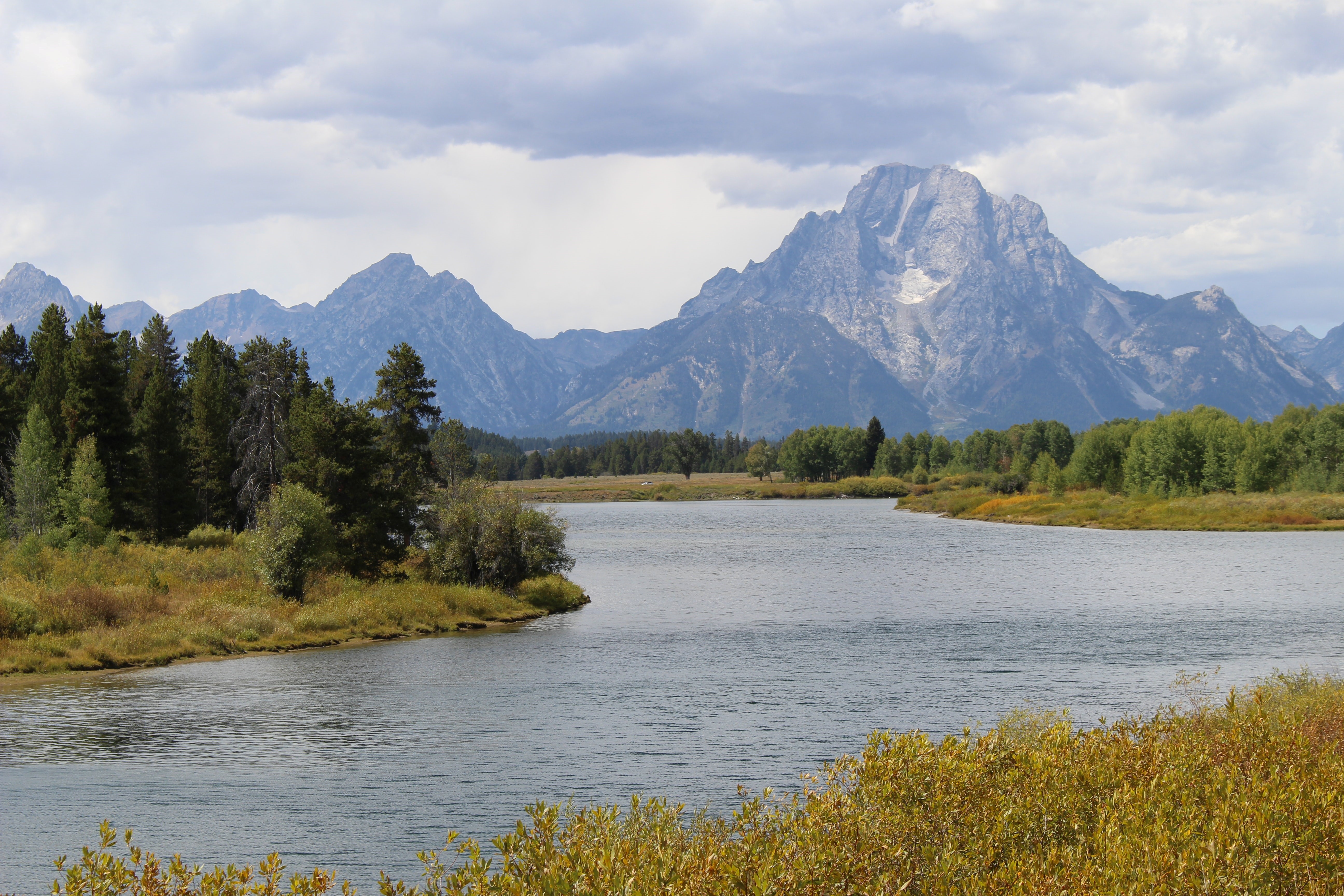 A view of the Snake River with the Tetons in the background on an overcast day.